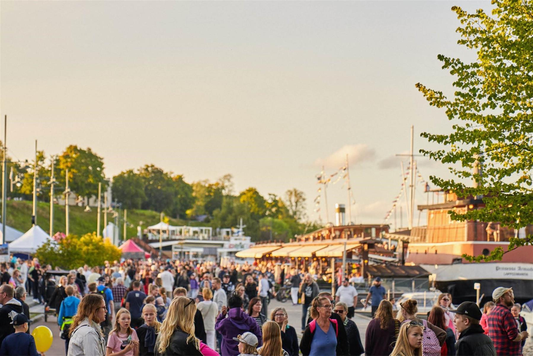 Lappeenrannan satamassa joukko ihmisiä ilta-auringossa. 